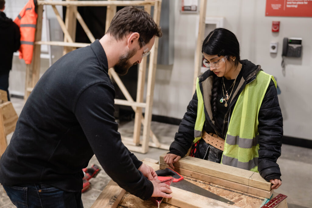 A student in WMCI's Carpentry 1 course learns framing from the instructor.