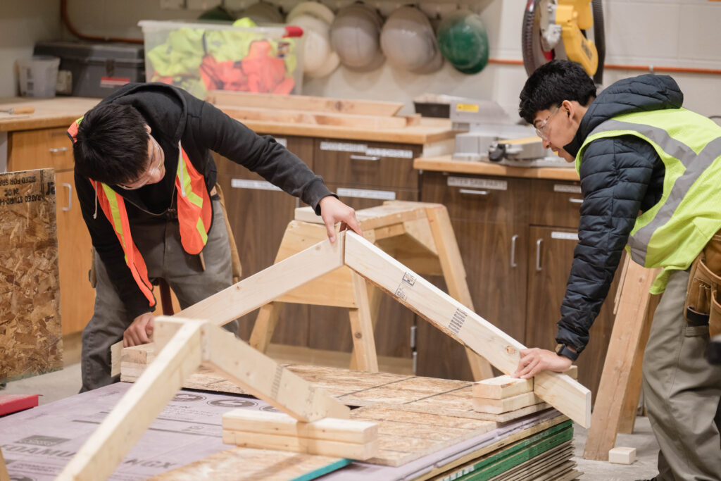 Two WMCI students in the Carpentry 1 and CORE course work on the framing of a structure.