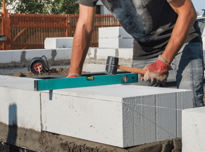 concrete finisher using a hammer to level a concrete block