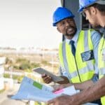 A construction leader instructs another construction worker on a project's safety elements