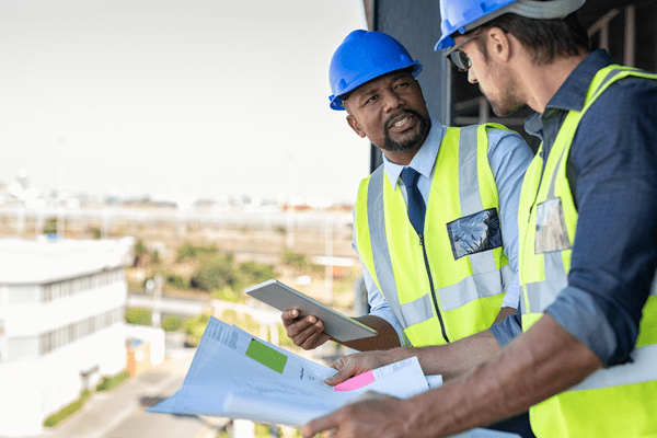 A construction leader instructs another construction worker on a project's safety elements
