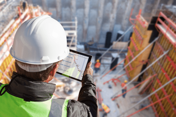 A construction worker on a job site uses a tablet to schedule activities and make plans