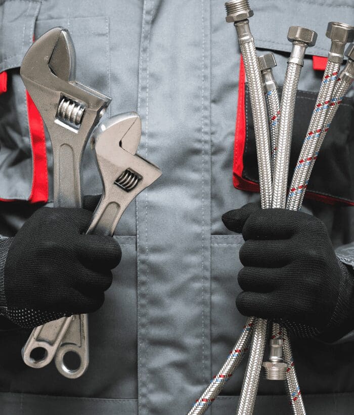 A Commercial Plumber is holding wrench and pipefitting tools