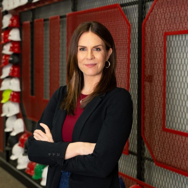 West Michigan Construction Institute Jen Schottke poses for a photo in front of the WMCI hard hat wall