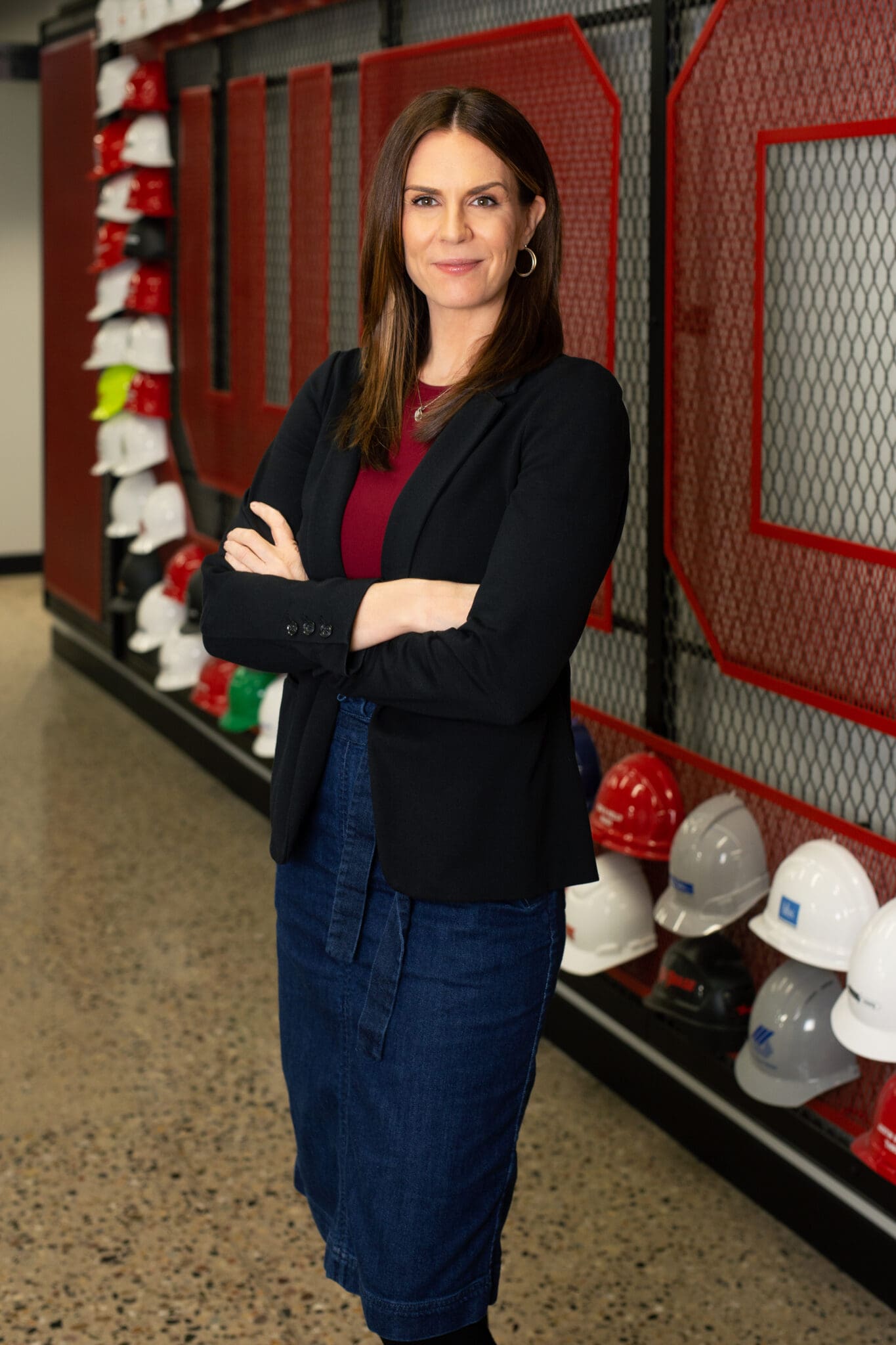 West Michigan Construction Institute Jen Schottke poses for a photo in front of the WMCI hard hat wall