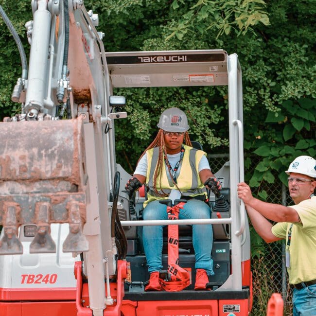 A female construction student learns how to operate an excavator at the West Michigan Construction Institute