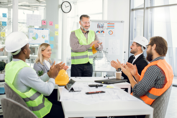 A foreman is concluding a successful construction presentation to a group of his clapping peers.