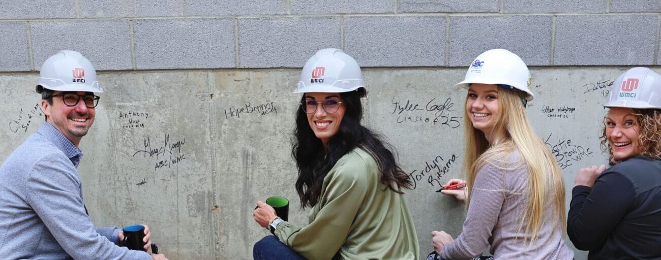 Group of Associated Builders & Contractors - West Michigan chapter sign the cinder blocks of the concrete lab at WMCI 2024 groundbreaking