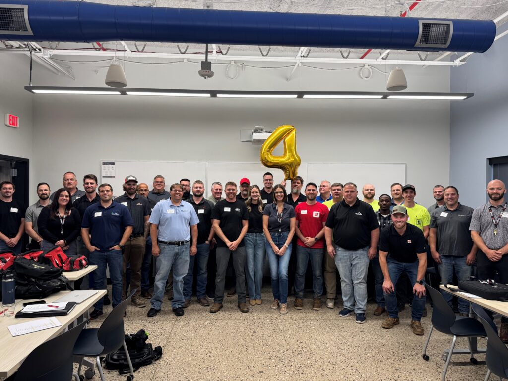 A picture of all the WMCI staff and instructors together in a classroom. There is a '4' balloon as they are celebrating the institution's 4th birthday.