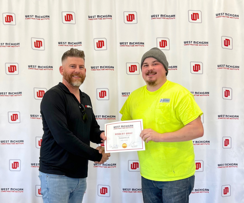 Carpentry 2 instructor congratulates recent graduate and provides certification.